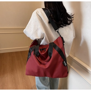 Model view of large burgundy and black tote bag with wide strap in cozy home interior