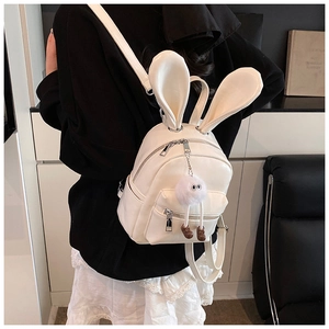 Close-up of a white faux leather mini backpack with rabbit ears and a fluffy charm