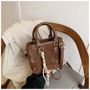Detailed close-up of brown marble textured handbag with golden hardware and braided pendant