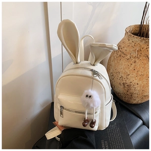 Detailed view of white PU leather backpack with 3D rabbit ears and fluffy pompom charm