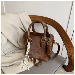 Detailed macro of dark brown textured mini bucket bag with gold hardware and woven charm
