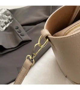Dettaglio ravvicinato della pelle martellata e del gancio metallico dorato sulla borsa beige