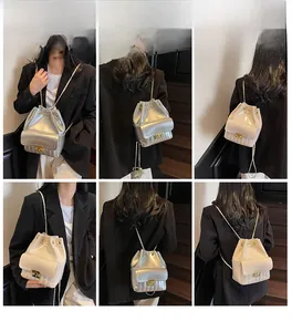Modella indossa borsa a secchiello lucida con tracolla a catena e dettagli trapuntati