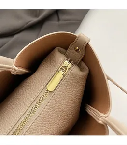 Dettaglio della cerniera dorata e della trama in pelle martellata della borsa beige