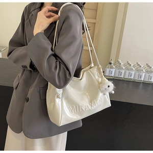 Chic white patent leather tote bag featuring embossed logo and fuzzy pompom accessory