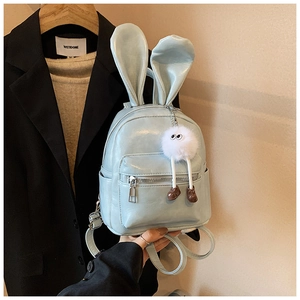 Detail of light blue mini backpack with bunny ears and white plush pendant accessory
