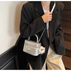 Detail of silver woven crossbody bag with chain strap and cute monster plush charm