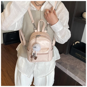 Detail of light pink mini backpack with cute white plush monster pendant accessory