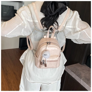 Detail of pearlescent pink mini backpack with cute monster charm and dual zippers