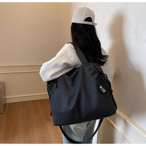 Detail of black nylon tote bag showing brand tag and durable shoulder strap