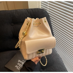 Dettaglio borsa a secchiello color crema in lana con catena d'oro su velluto nero