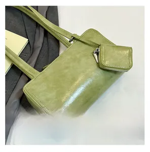 Detail view of grass green leather shoulder bag with matching mini coin purse and long strap