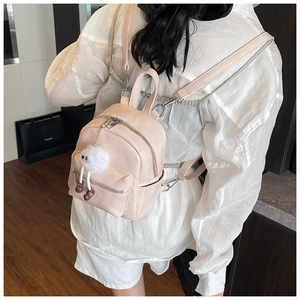 Pink mini PU leather backpack detail with a cute plush monster charm on the front pocket