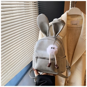 Detail view of mini grey PU leather backpack with bunny ears and plush monster charm