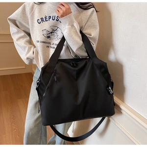 Detailed view of black nylon tote bag showing adjustable straps and side zipper pockets