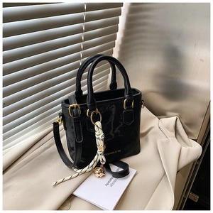 Detail of black faux leather bucket bag with gold hardware and stylish knot charm