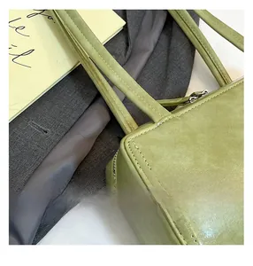 Close-up of fine stitching and edge finishing on avocado green rectangular shoulder bag