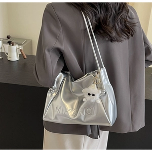 Detail of silver metallic underarm bag with logo embossing and plush cartoon charm