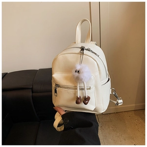 Close-up of off-white mini PU leather backpack with a plush monster charm in hand