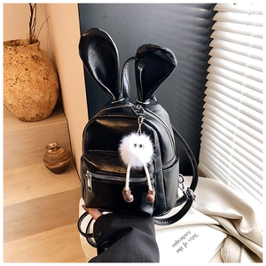 Detail of black faux leather backpack with rabbit ears and plush charm in elegant setting
