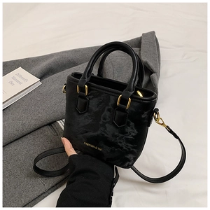 Close-up of black marble-textured bucket bag with golden hardware and long strap