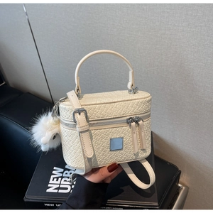 Close-up of cream box bag with crocodile pattern and silver zipper detail