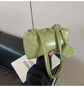Close-up of green oil wax leather Boston bag featuring double straps and matching pouch