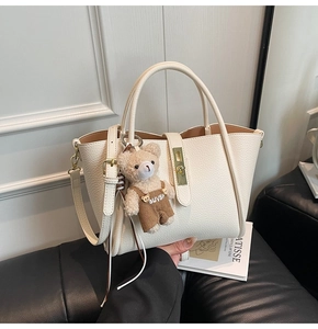 Borsa tote bianco crema in pelle martellata con fibbia dorata e ciondolo a orsetto