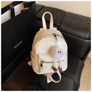 White PU leather mini backpack with a purple furry charm shown in a lifestyle setting