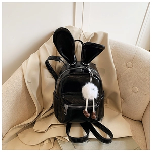 Detail of black glossy mini backpack with bunny ears and white plush doll charm