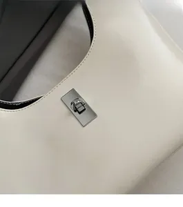 Detailed macro view of the silver metal twist lock on a creamy white leather handbag