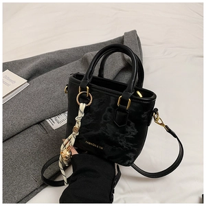 Detail of black handbag with gold ring hardware and check pattern silk scarf accent
