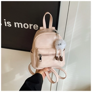 Detail of pink mini backpack with smooth leather surface and cute monster plush pendant