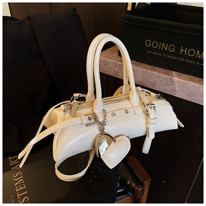 Detalle de un bolso tipo almohada blanco crema con asas dobles y amuleto de espejo