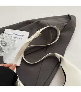 Detail view of the cream leather shoulder strap with silver buckle on a stylish crescent bag