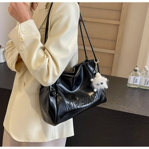 Detail of black pleated PU leather tote bag with embossed MIKAXIQI logo and plush charm