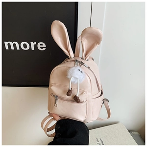 Pink mini backpack detail featuring rabbit ears and a white plush pompom charm