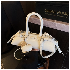 Detalle del bolso de hombro en charol blanco con correas de hebilla y colgante de corazón
