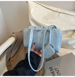 Close-up of light blue rectangle shoulder bag with matching mini charm and double zippers