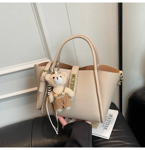 Dettaglio borsa in pelle martellata bianco crema con chiusura oro e ciondolo orso