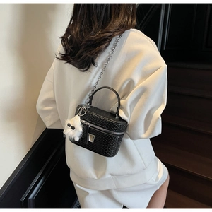 Detail of black woven box bag with silver hardware and white plush monster charm