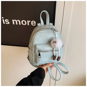 Close-up of light blue PU leather backpack featuring a cute white plush monster pendant