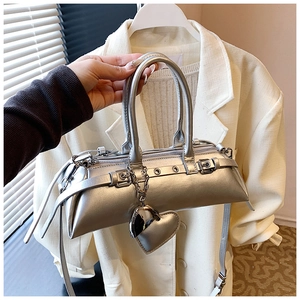 Detalle del bolso plateado con acabado metálico, hebillas de cinturón y dijes de corazón