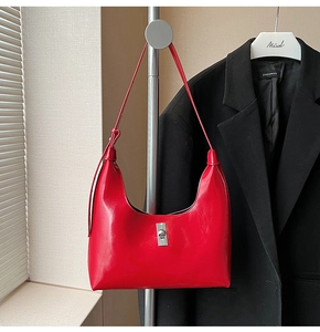Detail of red patent leather crescent bag featuring a silver twist lock and glossy finish