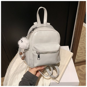 Close-up of a white mini backpack with a fluffy plush charm and adjustable PU straps