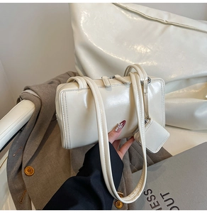 Close-up of cream glossy leather shoulder bag with a matching mini pouch charm