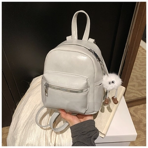 Close-up of mini white PU leather backpack with a cute white plush ball charm