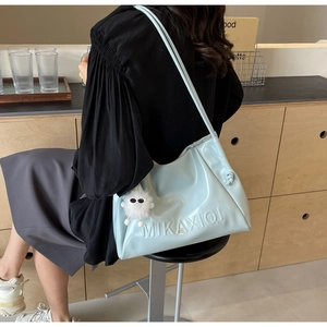 Detail view of light blue PU tote bag with embossed letters and white pompom charm