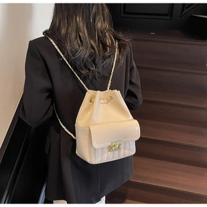 Détail du sac à dos seau crème avec cordon, cuir brillant et bretelles à chaîne dorée
