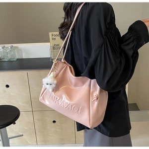 Detail of pink glossy PU leather tote bag with embossed logo and plush cat charm